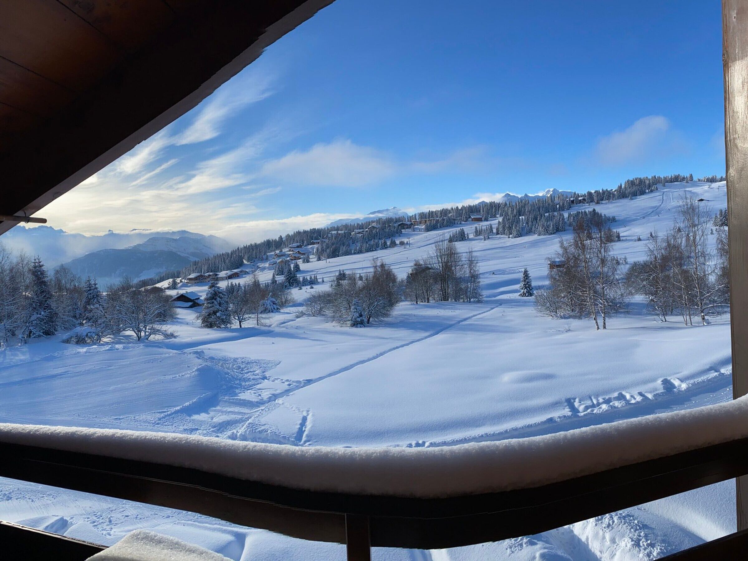 A snowy landscape with a clear sky, a wooden structure, and a distant village.