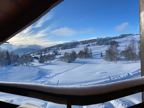 A snowy landscape with a clear sky, a wooden structure, and a distant village.