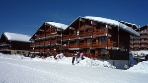 A multi-story wooden building with balconies, surrounded by snow. - Studio cabin 5 pers. with south balcony and GARAGE, Les Saisies (Les Saisies)