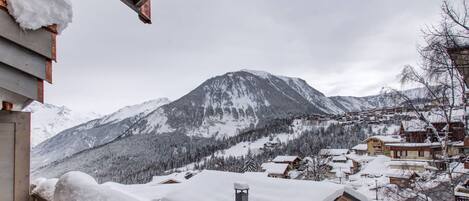 A mountain village with snow-covered buildings and a prominent mountain in the background.