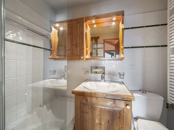 Une salle de bain avec deux lavabos, un meuble-lavabo en bois, un miroir et des toilettes.