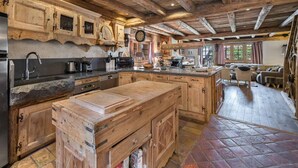 A rustic kitchen with wooden cabinets, a large island, and a stone countertop. - Authentic chalet with jacuzzi, sauna and parking for 12 people (Méribel)