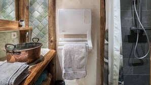 A bathroom with a wooden vanity, a white toilet, a shower area with a glass door, and a copper pot on the vanity. - Authentic chalet with jacuzzi, sauna and parking for 12 people (Méribel)