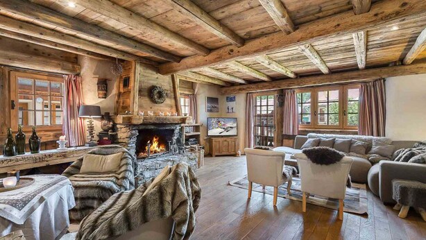A rustic interior with a stone fireplace, wooden beams, and a cozy seating area. - Authentic chalet with jacuzzi, sauna and parking for 12 people (Méribel)