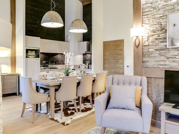 A modern kitchen with a dining area, featuring a cowhide rug, a grey armchair, and pendant lighting. - 4-room apartment near slopes with parking and wifi (Courchevel 1550)