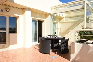 Ein Balkon mit Tisch, Stühlen, einer Glastür und Blick zum Himmel.