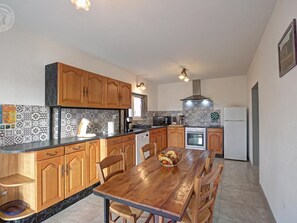 Une cuisine avec des meubles de rangement en bois, un pare-feu en carrelage, une cuisinière et un réfrigérateur.