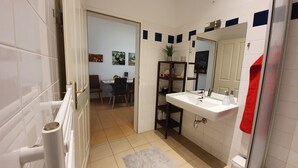 A bathroom with white tiles, a sink, a mirror, and a red towel. - Gorgeous Viennese Apartment/10 min to City Center (Wien)
