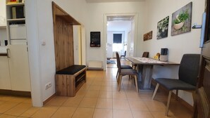 A modern kitchen with white cabinets, a wooden bench, and a dining area with a table and chairs. - Gorgeous Viennese Apartment/10 min to City Center (Wien)