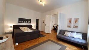 A bedroom with a bed, a sofa, a dining area, and a kitchen in the background. - Gorgeous Viennese Apartment/10 min to City Center (Wien)