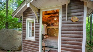 Una cabaña rústica de troncos con un interior acogedor, una gran roca en el exterior y un porche de madera.