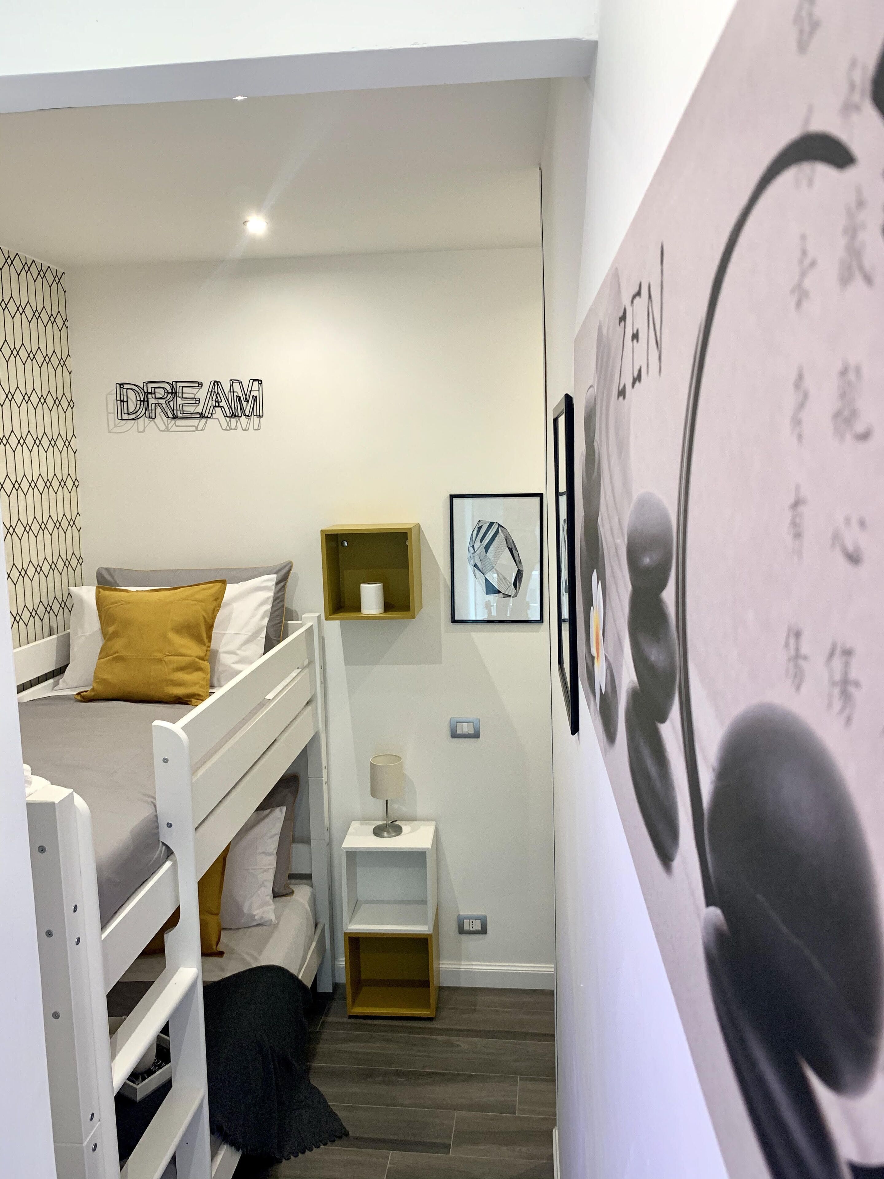A bedroom with a bunk bed, a bedside table with a lamp, and a wall with motivational words.
