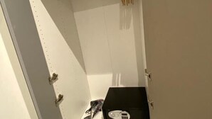 A small, enclosed space with a white shelf unit containing a black box, a pair of scissors, and a small item. - 4VaticanRooms (Rome)