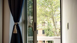 A room with a sliding glass door leading to an outdoor area with a tiled floor and a view of buildings and trees. - 4VaticanRooms (Rome)