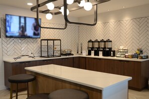 A modern kitchen with a large island, bar stools, a television mounted on the wall, and kitchen appliances. - Staybridge Suites Nashville SE - Murfreesboro by IHG (Murfreesboro)