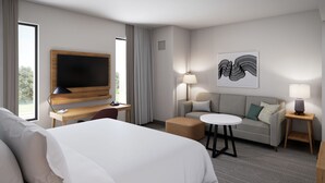 A hotel room with a large bed, a desk with a flat-screen TV, a sofa, a small round table, and two bedside lamps. - Staybridge Suites Nashville SE - Murfreesboro by IHG (Murfreesboro)