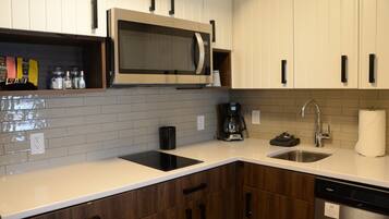 A modern kitchen with a built-in microwave, coffee maker, and dishwasher.