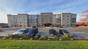 A Staybridge Suites hotel with a brick facade, multiple parking spaces, and a landscaped entrance area. - Staybridge Suites Nashville SE - Murfreesboro by IHG (Murfreesboro)