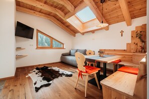 Une pièce chaleureuse avec un plafond en bois, une télévision, un canapé, une table à manger et un tapis en peau de vache.
