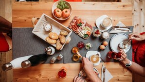 A wooden table with various food items, a coffee cup, and a bottle. - Apartment 'Bawiglbach Grosskarneid' with Mountain View, Shared Terrace and Wi-Fi (Lüsen)