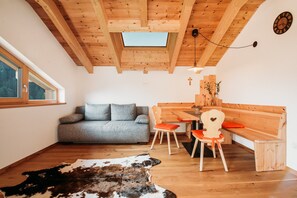 Une pièce chaleureuse avec un plafond en bois, un canapé, une table à manger avec des chaises et un tapis en peau de vache.