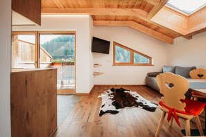 A room with wooden flooring, a cowhide rug, a television, and a dining area with a chair and table.