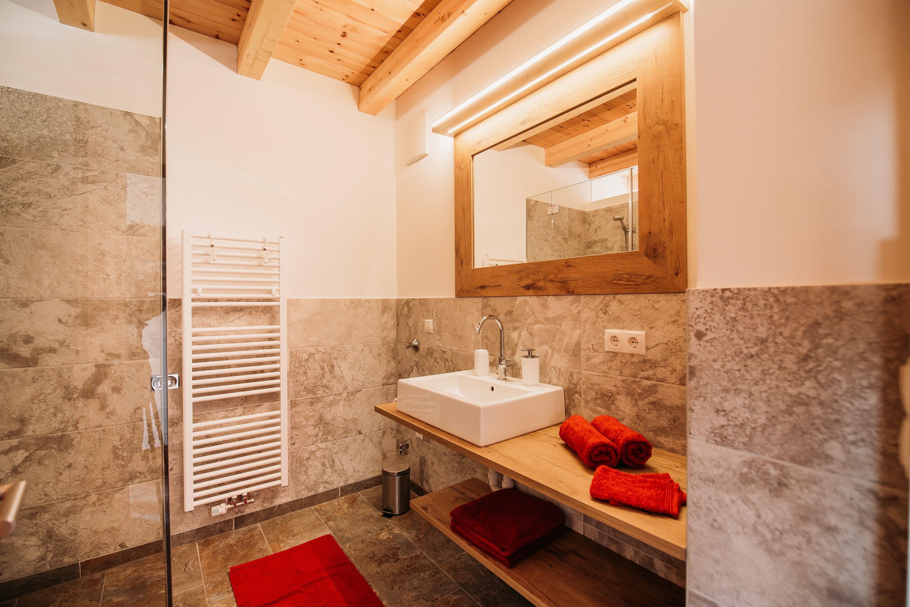 Une salle de bain avec une douche à parois de verre, un meuble-lavabo en bois et un miroir au-dessus.