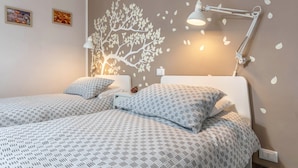 Une chambre avec deux lits, une peinture murale, un bureau et une lampe de bureau.