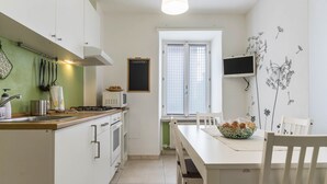 Une cuisine avec des meubles blancs, un four à micro-ondes, une cuisinière et une table à manger avec des chaises.