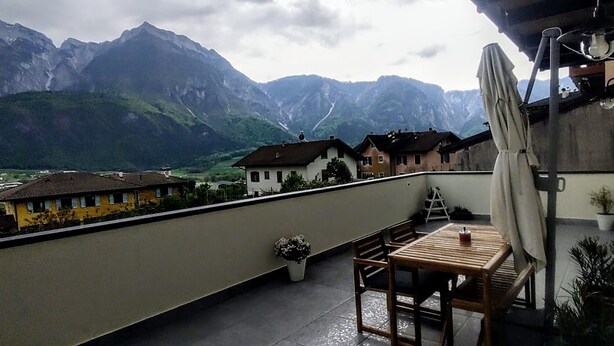 Un balcon avec vue sur les montagnes, une table, des chaises et une plante en pot.