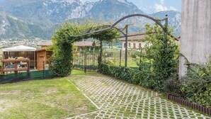 Une cour avec un chemin dallé aux motifs géométriques, une structure en bois et une vue sur les montagnes.