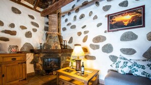 Una habitación acogedora con una chimenea de piedra, una mesa de madera con una lámpara y un sofá.