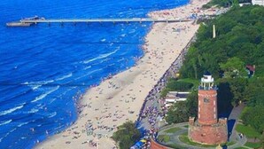 An aerial view of a beach with a lighthouse and a pier extending into the water. - Hotel Hanseatic  - adults only (Kolobrzeg)
