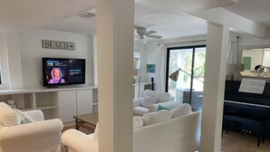 A living room with a television, a piano, and a couch. - Enjoy our Private Beach Access! (Vero Beach)