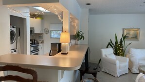 A compact living space with a kitchenette, a dining area, and a seating area with white furniture. - Enjoy our Private Beach Access! (Vero Beach)
