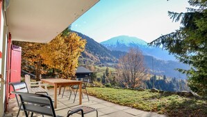 Une terrasse avec une table et des chaises, offrant une vue sur un paysage montagneux.