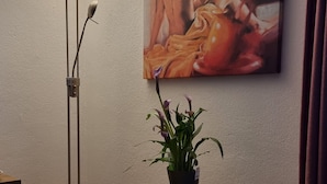 Une pièce avec une table ronde en bois, un lampadaire et un tableau accroché au mur.