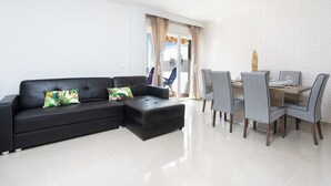 A modern living room with a black sectional sofa, grey chairs, and a dining table.