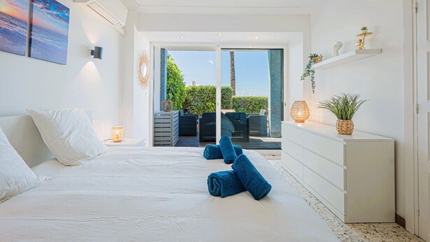 Une chambre à coucher avec un lit, une table de chevet, une commode et une vue sur l’extérieur.