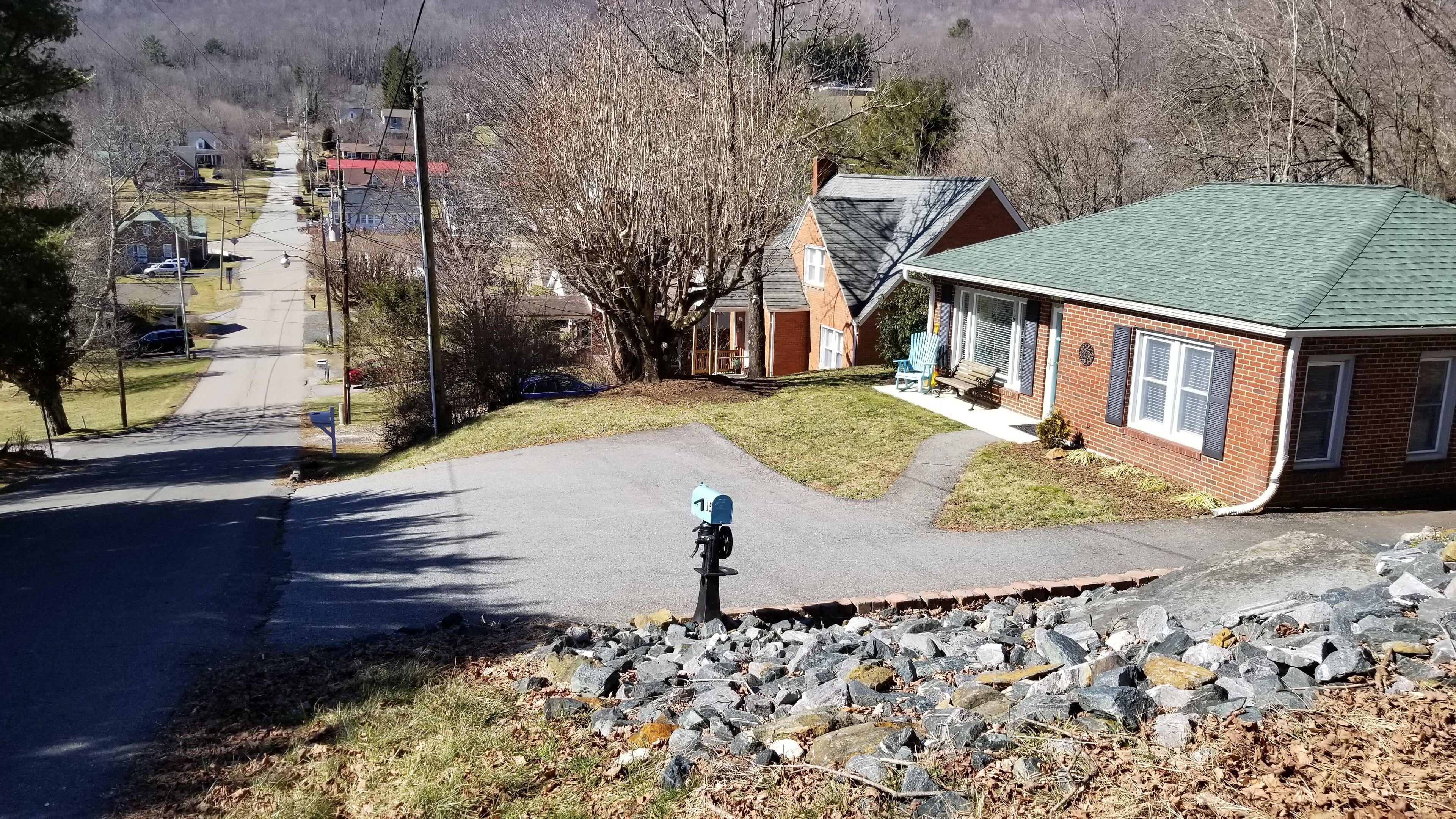 Una calle residencial con casas, un buzón y un muro de piedra.