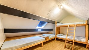 Ein Schlafsaalzimmer mit zwei Etagenbetten, einem Dachfenster und Holzboden.