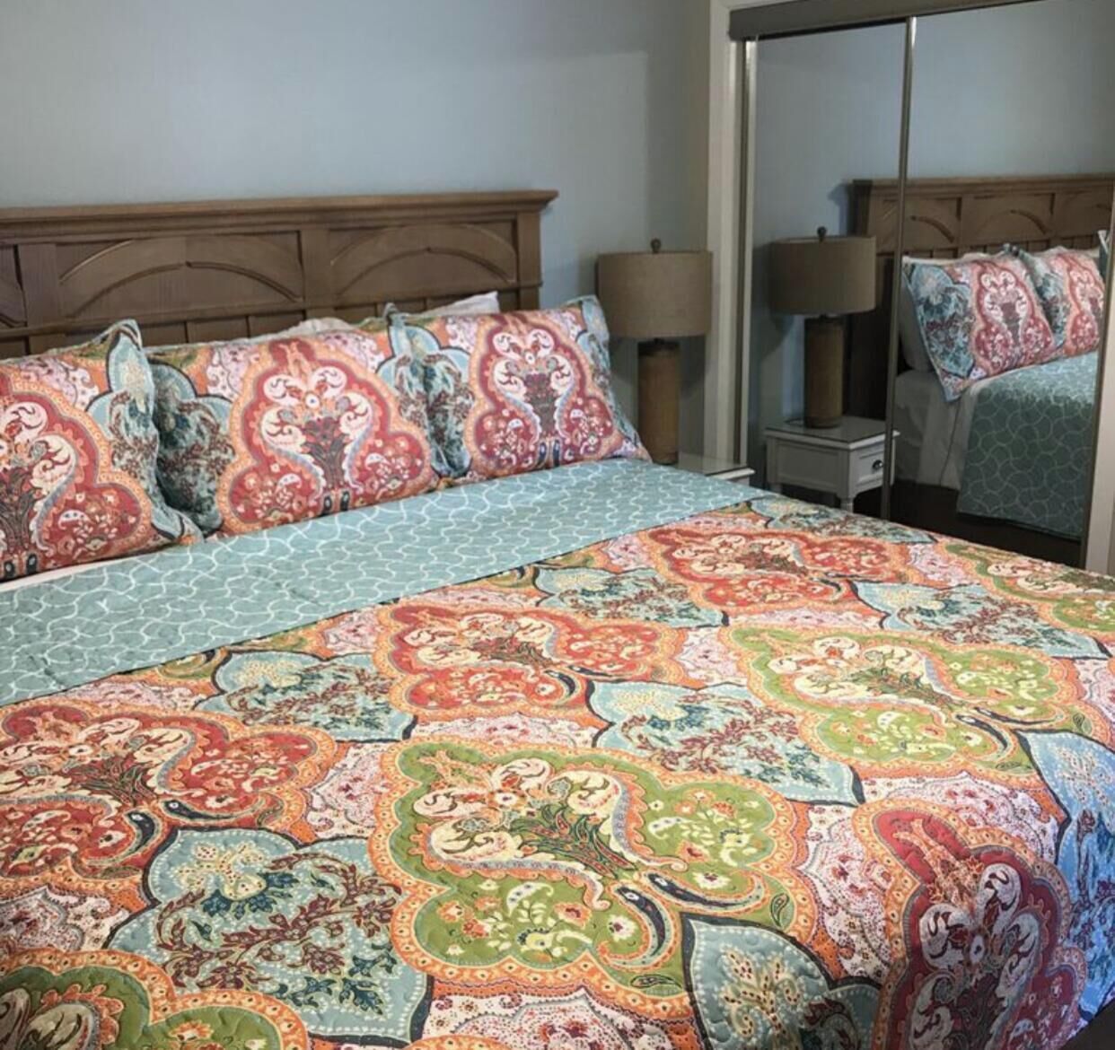 Ein Schlafzimmer mit einem großen Bett, zwei Nachttischen und einem Spiegel.