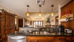 A kitchen with a large island, wooden cabinets, and pendant lighting.