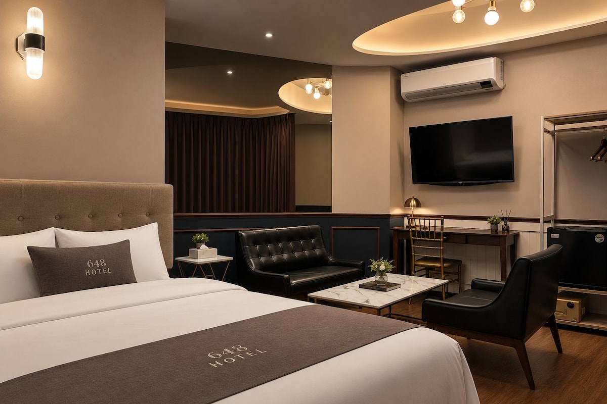 A hotel room with a large bed, a desk, a television, and a wardrobe.