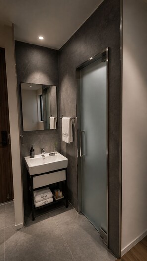 A modern bathroom with a dark wall, a white sink, a mirror, and a frosted glass door. - 648 Hotel (Seoul)