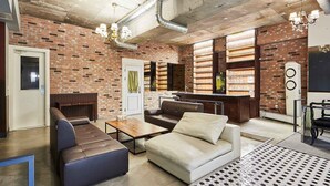 A modern living room with a brick wall, leather sofas, a coffee table, and a bar area with shelves. - 648 Hotel (Seoul)