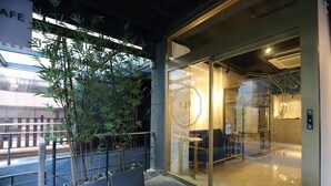 Entrada de un hotel con puertas de vidrio, un cartel que dice 'Hotel Classic Boutique' y una pequeña planta de interior.