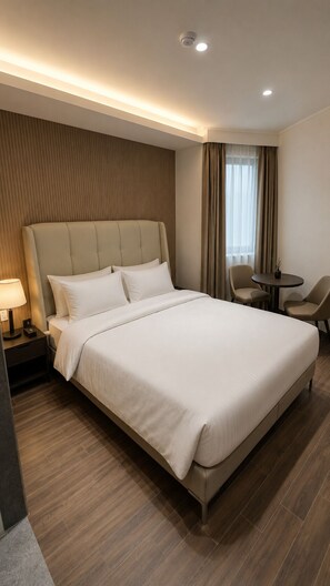 A hotel room with a large bed, a bedside table with a lamp, a small round table, and a chair. - 648 Hotel (Seoul)