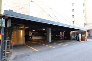 A parking garage entrance with a covered walkway, a vending machine, and a car parked inside.