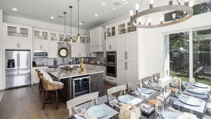 A spacious kitchen with white cabinetry, stainless steel appliances, and a large island. - Whispering Waters - Lakefront Luxe, Pool + Hot Tub + Fire Pit + Outdoor Kitchen + 2 Master Suites (Canyon Lake)